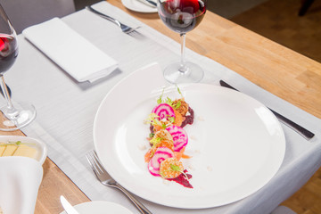 Smoked salmon with roasted beetroots sauce, russian pancakes and horseradish cream served in a restaurant