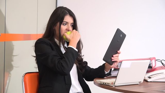 Relaxing indoors office eat fruits female executive leader watch movie on tablet