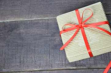 image of Valentine present on a table. packaged box with a gift tied with a red ribbon