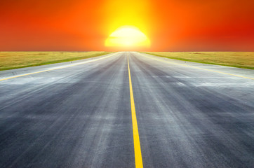 Naklejka premium Runway at the airport the horizon at sunset in the center of the sun.