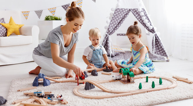 family mother and children play a toy railway in   playroom