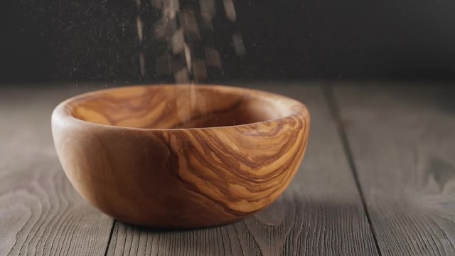 oat flakes falling into wood olive bowl closeup slow motion footage