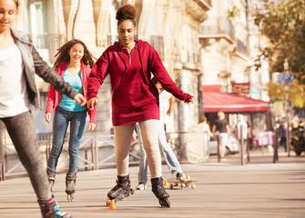 African teenage girl rollerblading at side walk