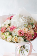 floral composition with roses and mix flowers in glass vase on a gray background.