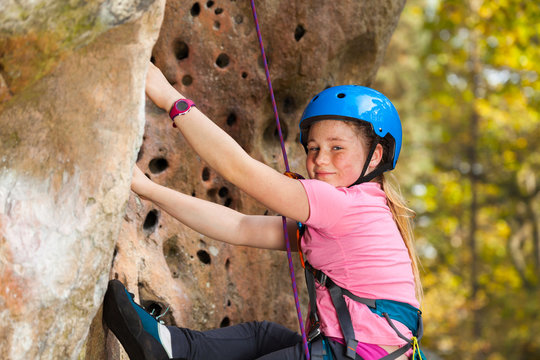 Girl in safety helmet climbing on the rock route