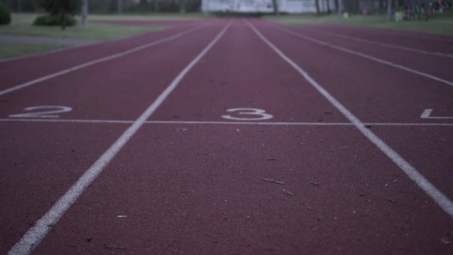 Runner running on school playground's empty track in the evening