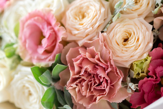 Close-up floral composition with roses and mix flowers on a light background.