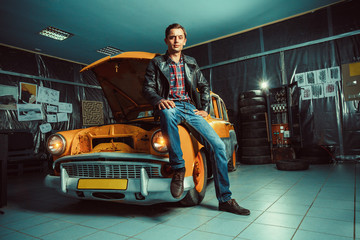 Smart driver is sitting on his old car in the garage