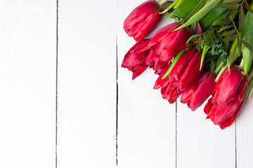 Bouquet of red tulips on white wooden background. Flat lay.