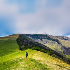 Barefoot tourist walks in spring green mountains.