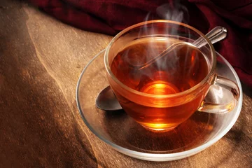 Photo sur Plexiglas Theé thé noir fraîchement infusé dans une tasse en verre, boisson chaude fumante sur bois rustique foncé, espace pour copie