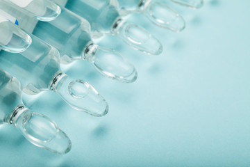 Glass ampoules with vaccine on a blue background. Copy space.