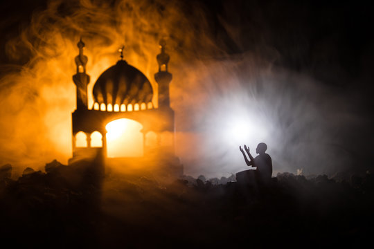 Silhouette of mosque building on toned foggy background. Ramadan Kareem background. Mosque at sunset. Praying people. Selective focus