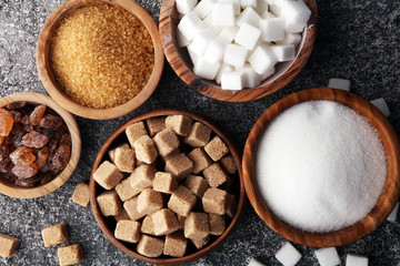 Various types of sugar, brown sugar and white on grey table