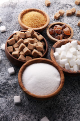 Various types of sugar, brown sugar and white on grey table