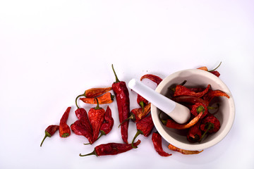 Dried peppers and white mortar on a white background.