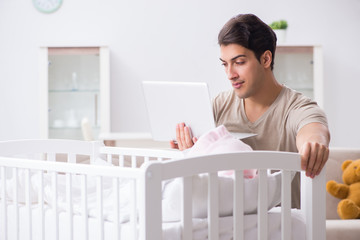 Young dad student preparing for exams and looking after baby