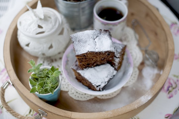 Chocolate cupcake with sugar and coffee. Breakfast on a wooden tray and flowers. 