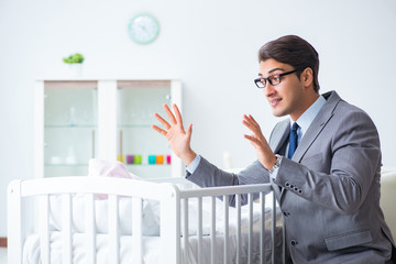 Young businessman trying to work from home caring after newborn baby