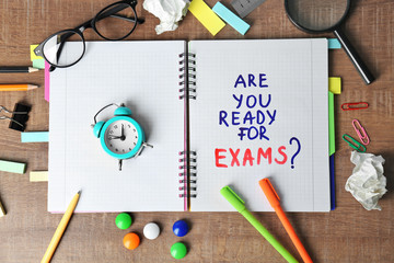 Notebook with question "Are you ready for exams?" and alarm clock on table