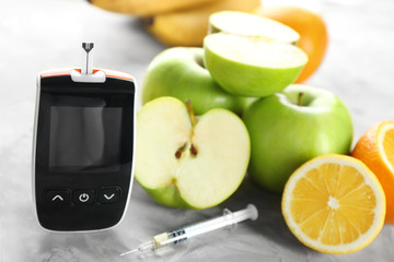 Digital glucometer, syringe and fruits on table. Diabetes diet