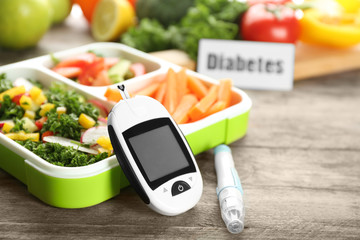 Digital glucometer, lancet pen and lunch box with vegetables on table. Diabetes diet - obrazy, fototapety, plakaty