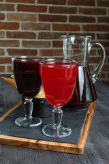 Cranberry morse with orange, apple and cinnamon in a glasses on a brown wooden background