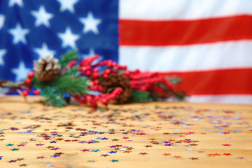 Confetti on wooden table against blurred American flag
