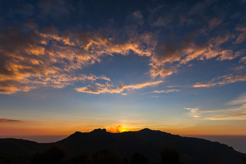 Red, orange, yellow clouds, with blue sky