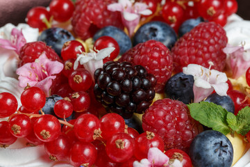 Meringue dessert cake with fresh berries on wood background