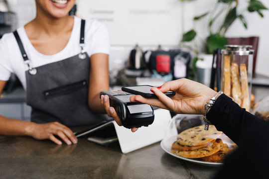 Customer making wireless payment using smartphone in cafe