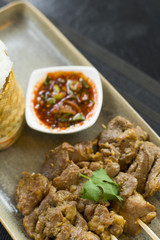 Grilled pork skewers and sticky rice served with spicy tamarind sauce, Thai street food