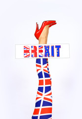 A model's legs are stretched out high in a vertical  form in front of a white background. The woman's  leotards have a British pattern on them. She holds  a Brexit sign between her legs.