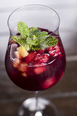 Purple fruit cocktail with raspberry and pineapple garnished with mint
