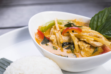 Thai red curry with chicken in white bowl served with rice