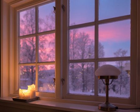 Pink sunrise seen from cosy cabin kitchen in winter landscape