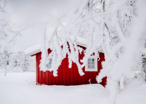 Tiny cute red cabin in winter white forest