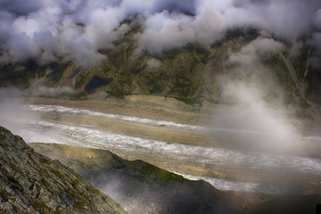 View on sunlit glacier through the clouds from a great height.