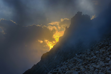 Golden cloudy sunset in the mountains with cliff. View from high altitude.