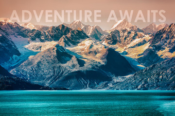 ADVENTURE AWAITS travel concept motivational quote written on nature landscape of Alaska mountain range in the wilderness. Inspirational quotes for the outdoors, go travel and discover.