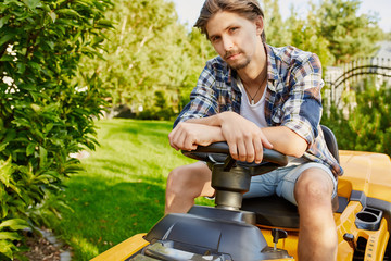 Young gardener man mowing the grass