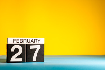 February 27th. Day 27 of february month, calendar on yellow background. Winter time. Empty space...
