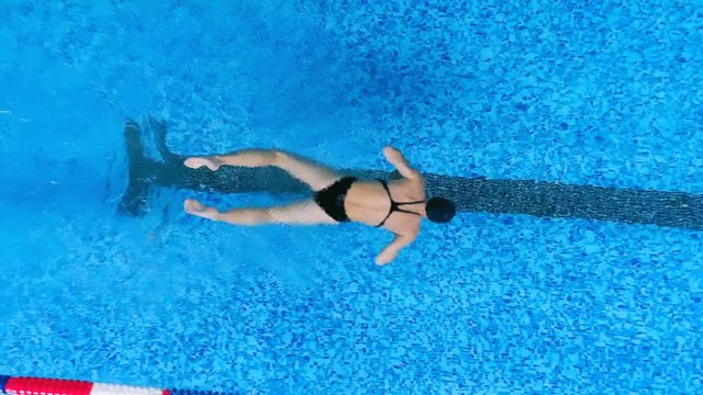 A swimmer uses her legs to swim under water. 