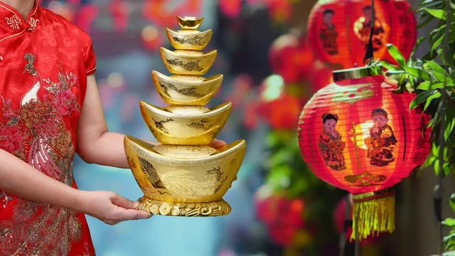 Woman holding Chinese new year gold ingots (qian) in chinatown