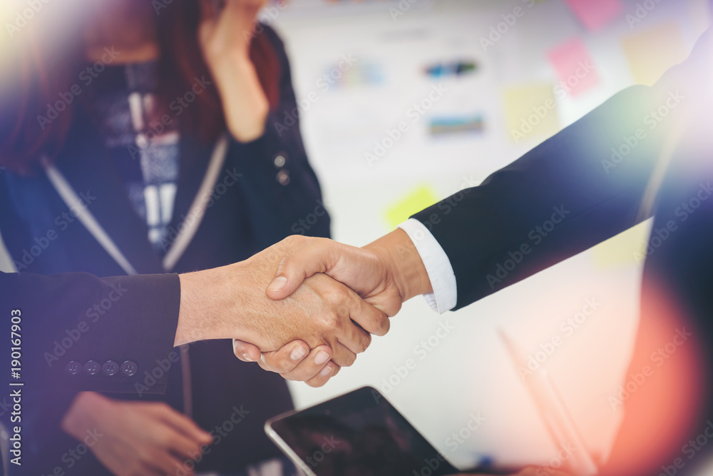 Wall mural Business people shaking hands while sitting at the working place, Finish success business good deals meeting