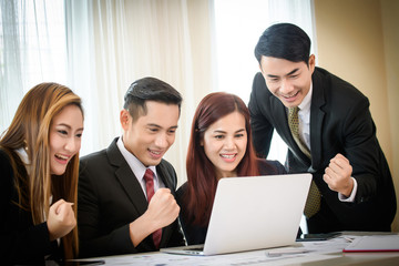 Happy business team enjoy good news together from email on laptop.