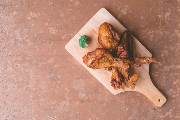 Top view of Fried chicken legs and wings on wooden tray.