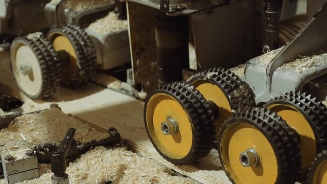 Rolling spiked wheels of board refiner machine working on wood at sawmill production, close up
