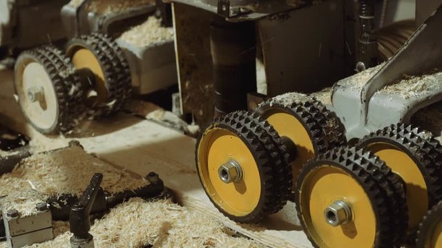Rolling spiked wheels of plank refiner machine working on wood at sawmill production, close up