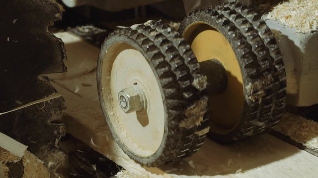 Rolling spiked wheels of board refiner machine working on wood at sawmill factory, close up